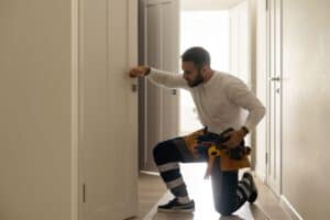 49291178 good looking man working as handyman and fixing a door lock in a house entrance