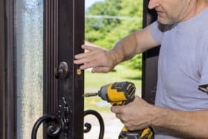 50029668 carpenter worker installing the lock on the entrance door of the new home e1682687307605